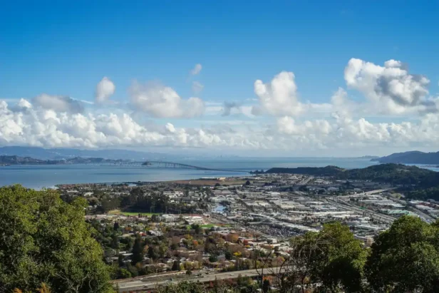 Morning sunlight illuminating Bay Area buildings and waterfront during golden hour sunrise.
