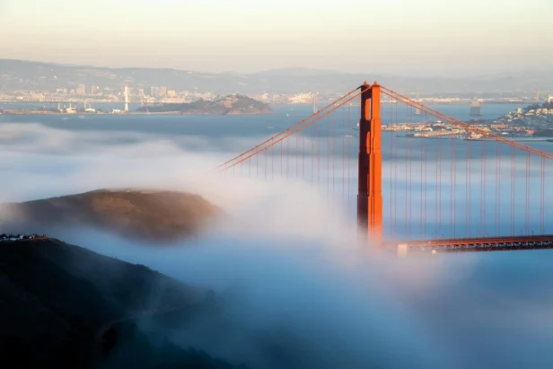 Golden Gate Bridge surrounded by thick morning fog at sunrise