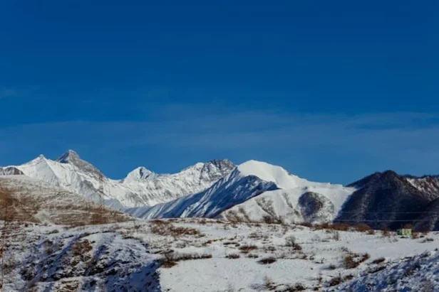Snow-covered Sierra Nevada mountain peaks show patches of bare rock and diminished snowpack during an unusually warm winter s